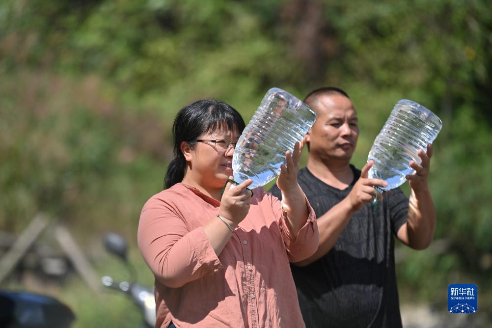 楊寧（左）在查看村民剛剛采集的水樣，為山泉水引水工程做準(zhǔn)備（10月8日攝）。新華社記者 黃孝邦 攝